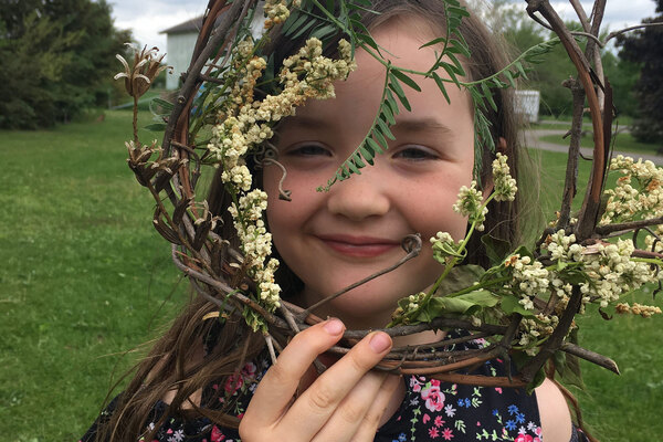 Child holds and looks through wreath